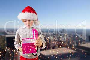 Composite image of festive boy holding a gift
