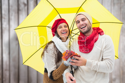 Composite image of autumn couple holding umbrella