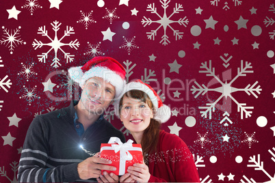 Composite image of couple holding a christmas gift