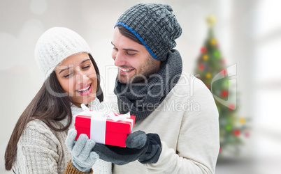 Composite image of winter couple holding gift Composite image of winter couple holding gift