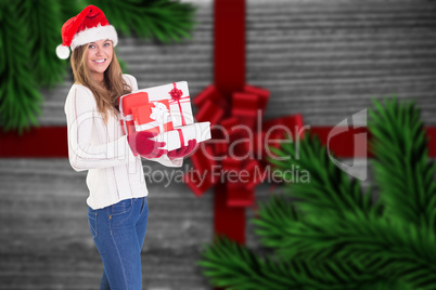 Composite image of festive blonde holding pile of gifts