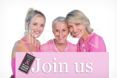 Composite image of embracing women wearing pink tops and ribbons
