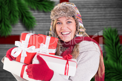 Composite image of happy blonde in winter clothes holding gifts