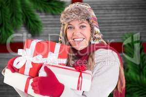 Composite image of happy blonde in winter clothes holding gifts