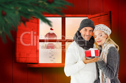 Composite image of happy winter couple with gift