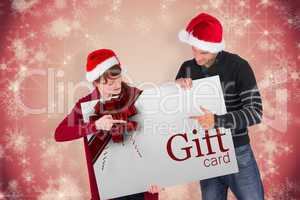 Composite image of couple holding a white sign