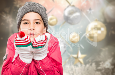 Composite image of wrapped up little girl blowing over hands