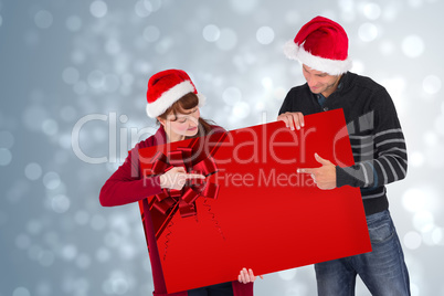 Couple holding a sign with red ribbon