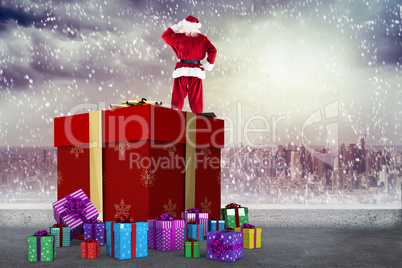 Composite image of santa standing on giant present