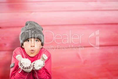 Composite image of wrapped up little girl blowing over hands