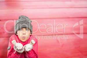 Composite image of wrapped up little girl blowing over hands