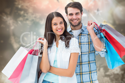 Composite image of happy couple with shopping bags