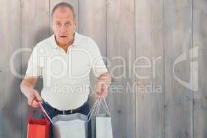 Composite image of shocked man holding shopping bags