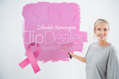 Composite image of happy young woman painting her wall pink