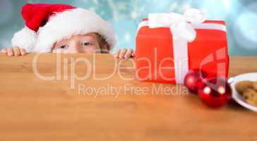 Composite image of festive boy peeking over table