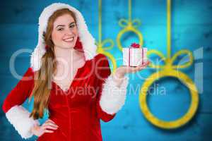 Composite image of pretty girl in santa costume holding gift box