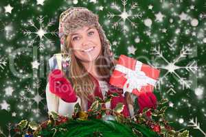 Composite image of happy blonde in winter clothes holding gifts