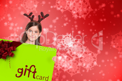 Composite image of festive little girl showing card