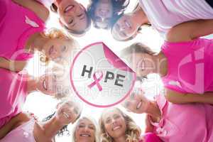 Composite image of cheerful women in circle wearing pink for bre