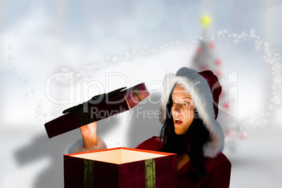 Composite image of surprised woman opening christmas present