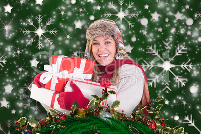 Composite image of happy blonde in winter clothes holding gifts