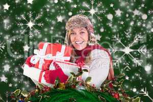 Composite image of happy blonde in winter clothes holding gifts