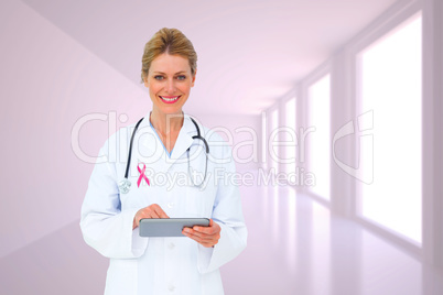 Composite image of blonde doctor using tablet pc Composite image of blonde doctor using tablet pc