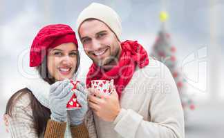 Composite image of winter couple holding mugs