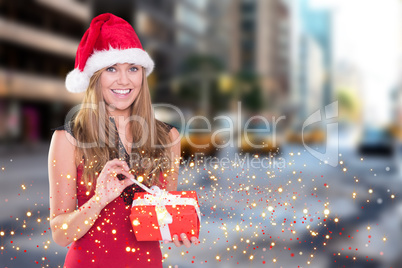 Composite image of festive blonde opening a gift