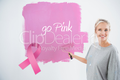 Composite image of happy young woman painting her wall pink