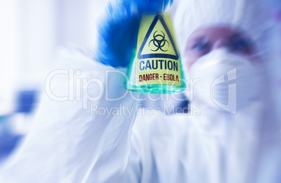 Scientist in protective suit holding beaker