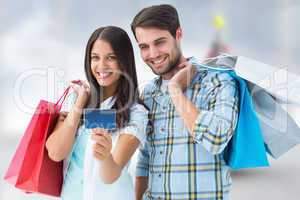 Composite image of couple with shopping bags and credit card