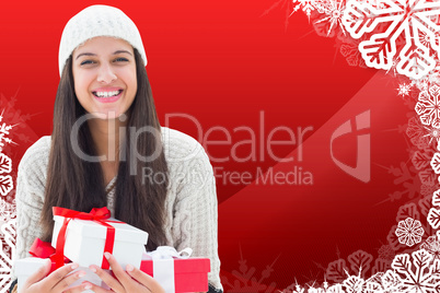 Composite image of festive brunette holding gifts