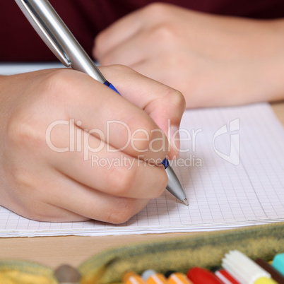 Schüler beim schreiben in sein Heft mit Hand in der Schule