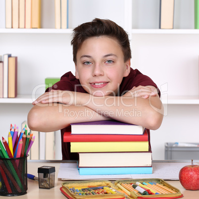 Lachender Schüler und ein Stapel Bücher in der Schule