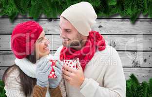 Composite image of winter couple holding mugs