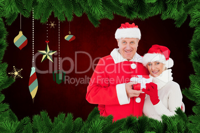 Composite image of festive mature couple holding gift