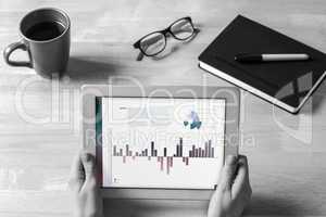 Composite image of businesswoman holding tablet at desk