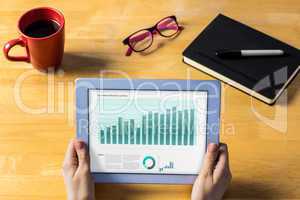 Composite image of businesswoman using tablet at desk