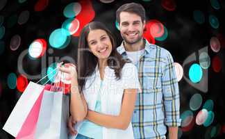 Composite image of happy couple with shopping bags