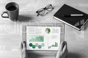 Composite image of businesswoman holding tablet at desk