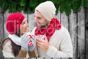 Composite image of winter couple holding mugs