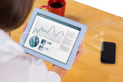 Composite image of businesswoman using tablet at desk