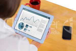 Composite image of businesswoman using tablet at desk