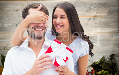 Composite image of woman surprising boyfriend with gift