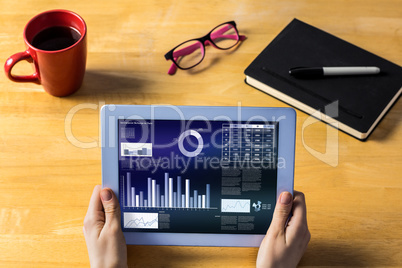 Composite image of businesswoman using tablet at desk