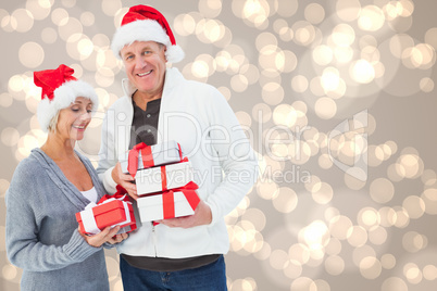 Composite image of festive mature couple holding christmas gifts