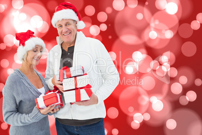 Composite image of festive mature couple holding christmas gifts