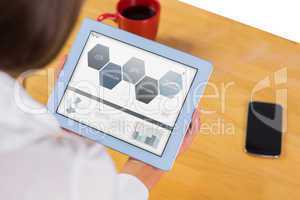 Composite image of businesswoman using tablet at desk