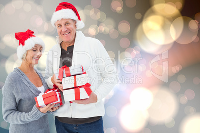 Composite image of festive mature couple holding christmas gifts